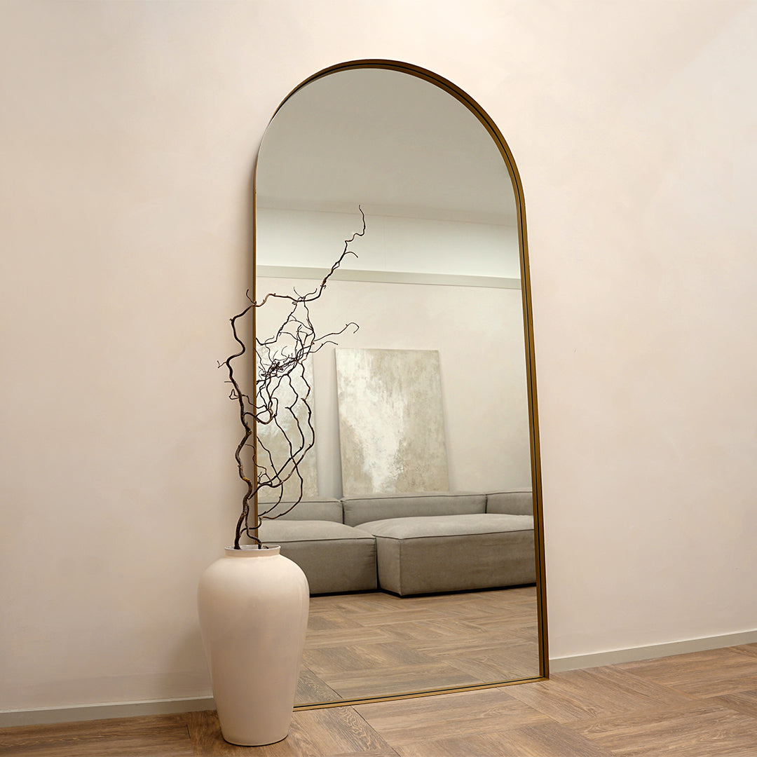 Full length arched gold extra large metal mirror leaning against wall