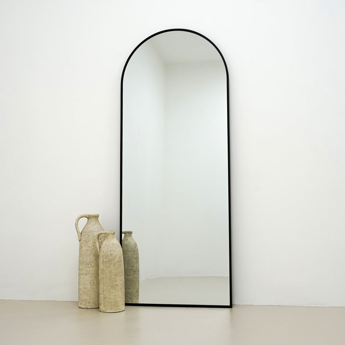 Black Full Length Arched Metal Mirror beside ceramic vases