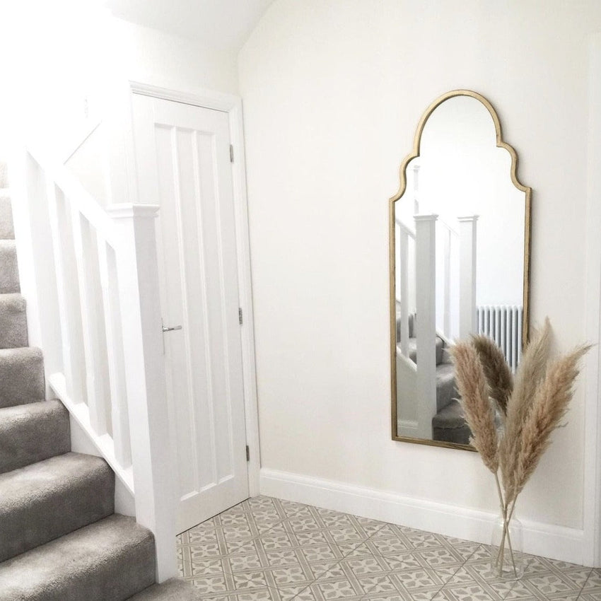 Gold industrial arched extra large metal mirror leaning against wall