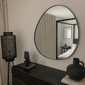 Black metal pond shaped irregular wall mirror displayed above console table