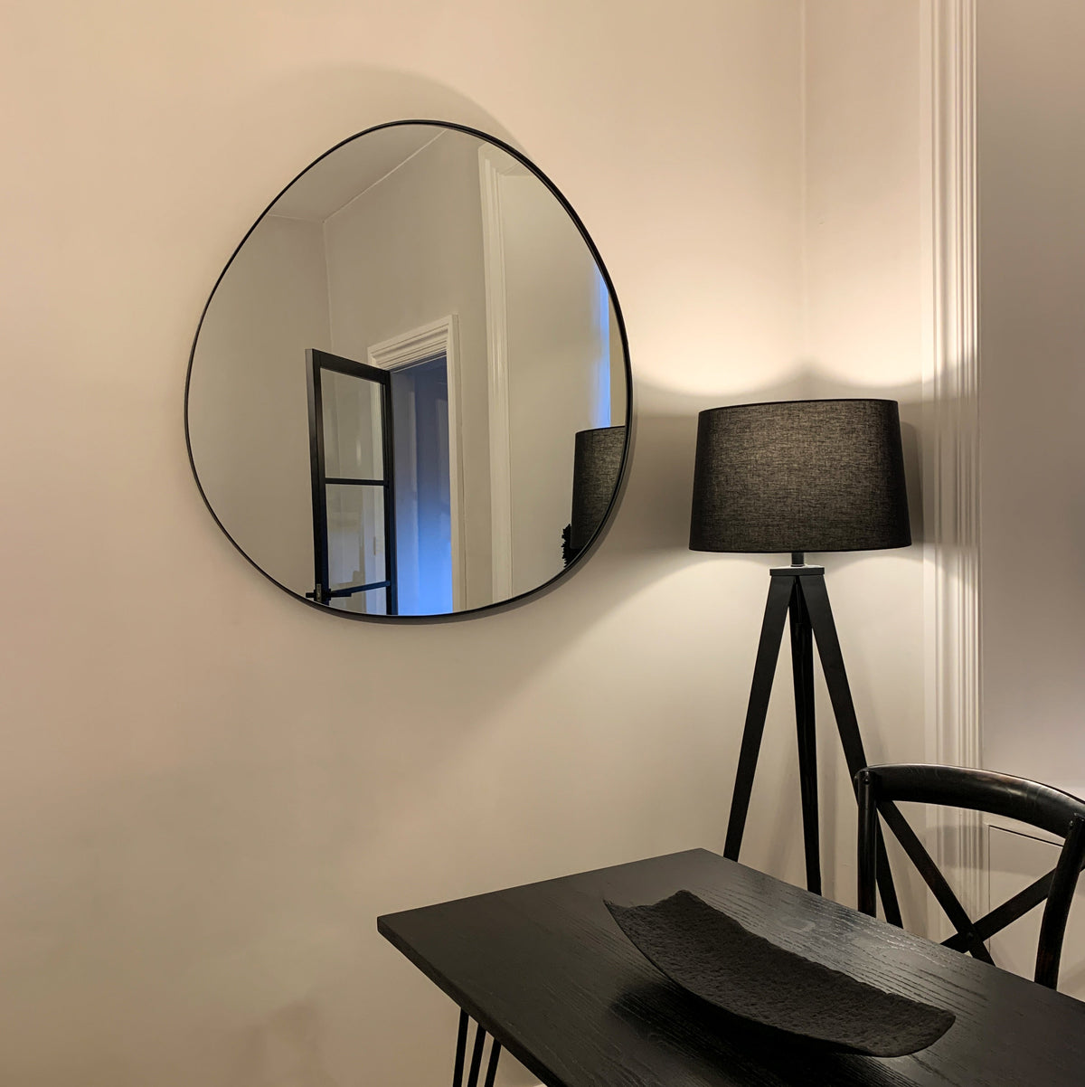 Black metal pond shaped irregular wall mirror displayed on wall