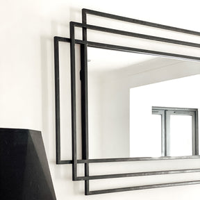 Large black rectangular metal mirror displayed on wall