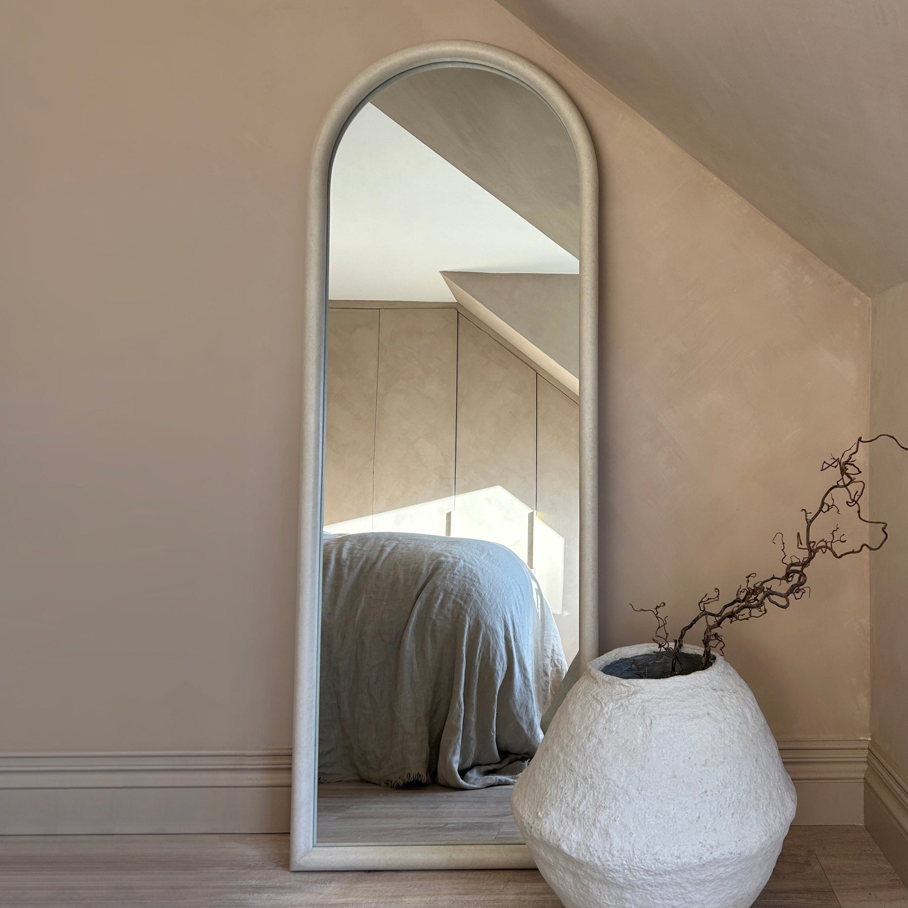 Large arched concrete mirror leaning against wall