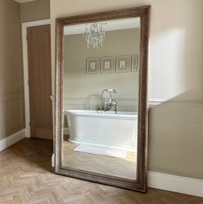 Full length washed wood rectangular mirror leaning against wall