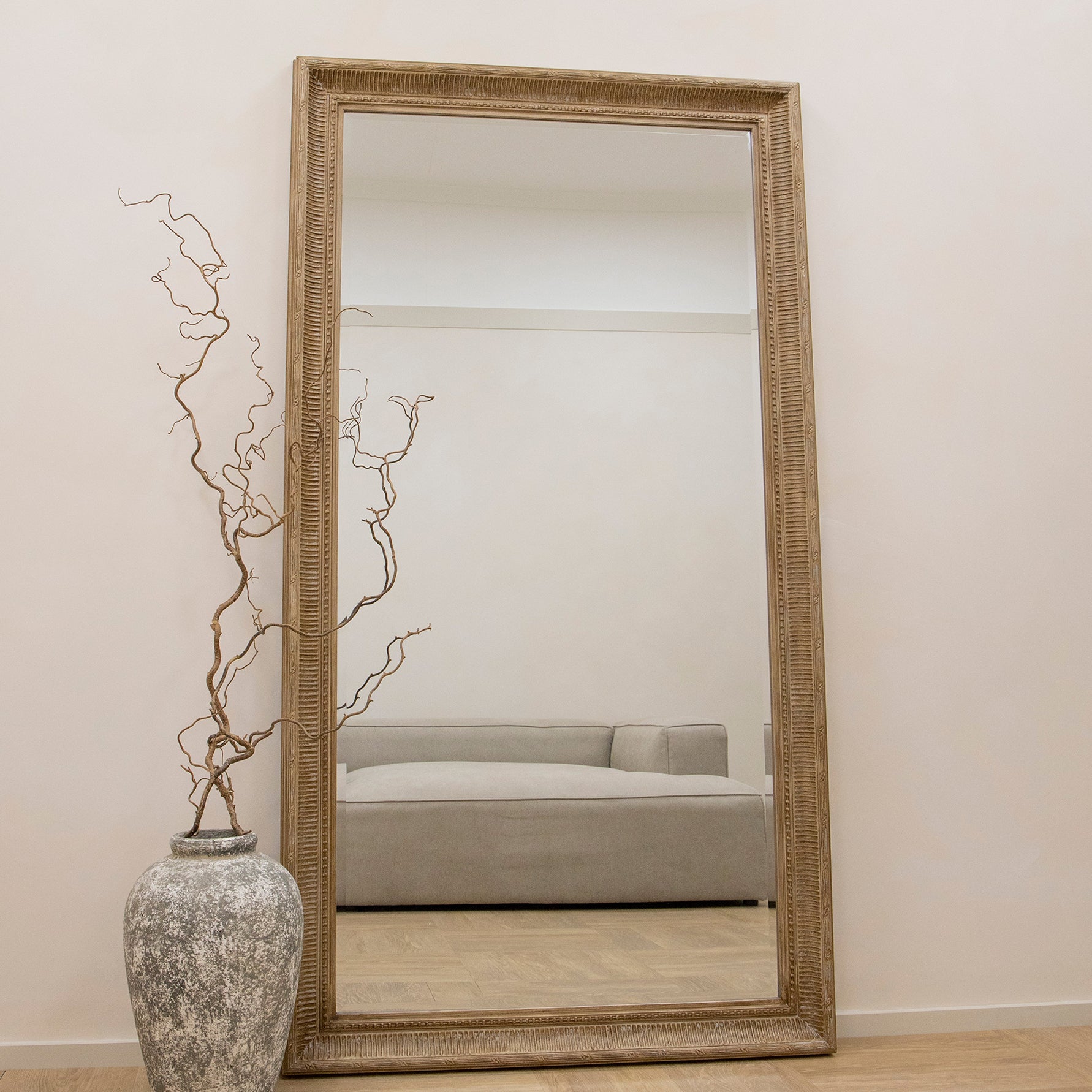 Full length washed wood rectangular mirror leaning against wall