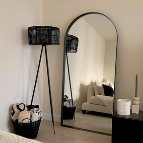 Full length arched black large metal mirror leaning against wall