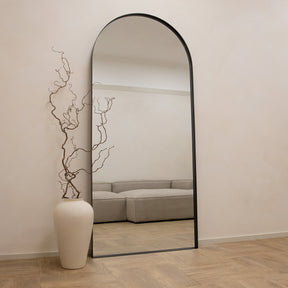 Full length arched black XXL metal mirror leaning against wall