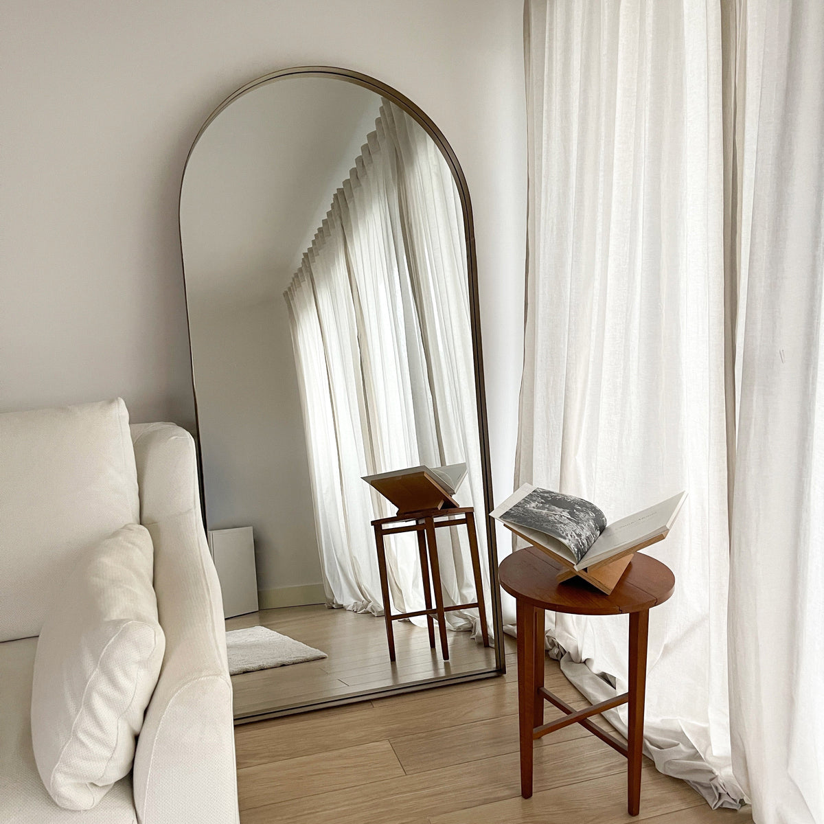 Full length arched gold large metal mirror leaning against wall