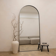 Full length arched black extra large metal mirror leaning against wall