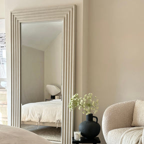 Full length ribbed concrete mirror leaning against wall