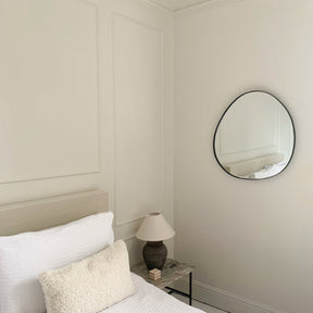 Black metal pond shaped irregular wall mirror displayed on wall