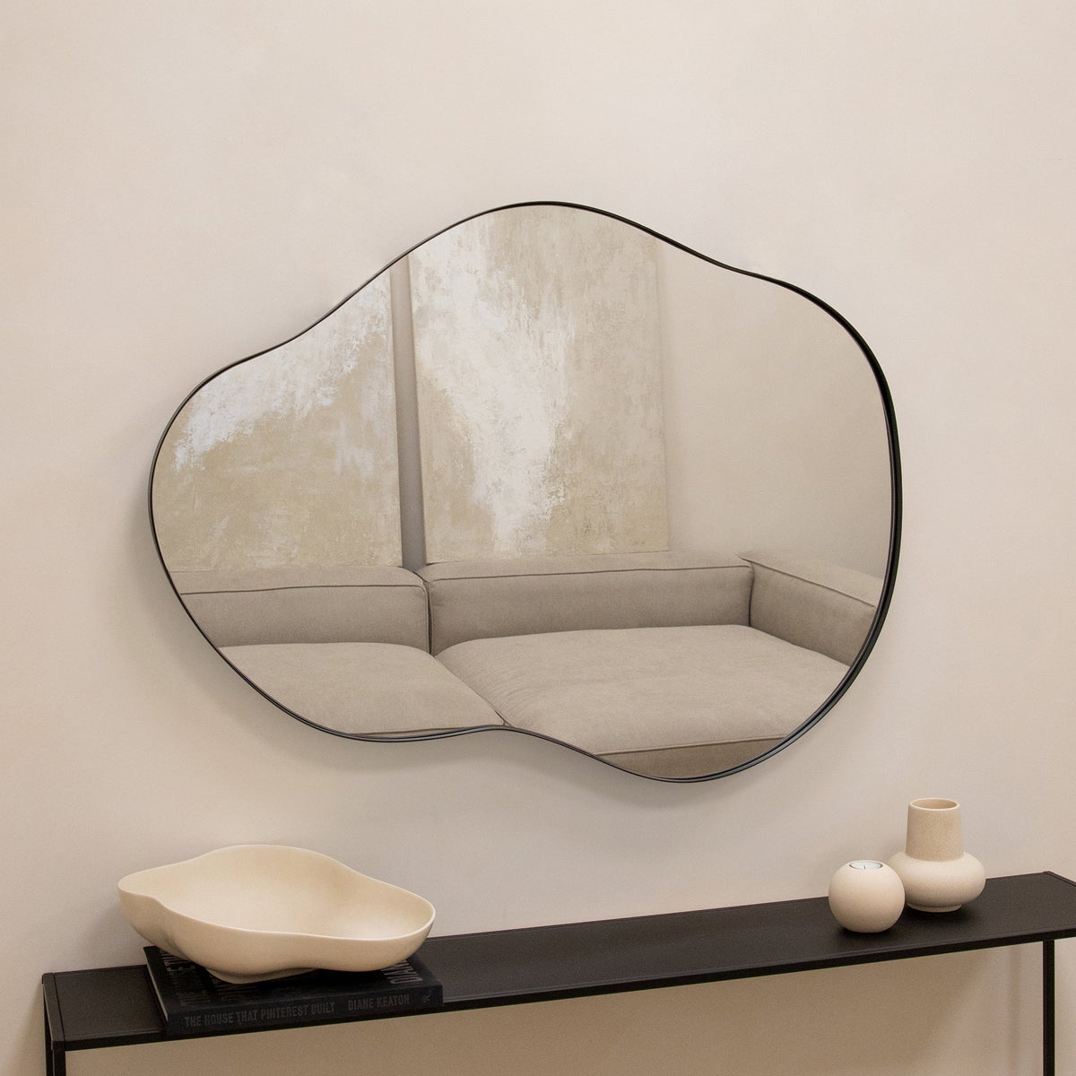 Black metal pond shaped irregular wall mirror displayed horizontally on wall