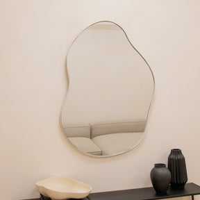 Ecru metal pond shaped irregular wall mirror displayed on wall