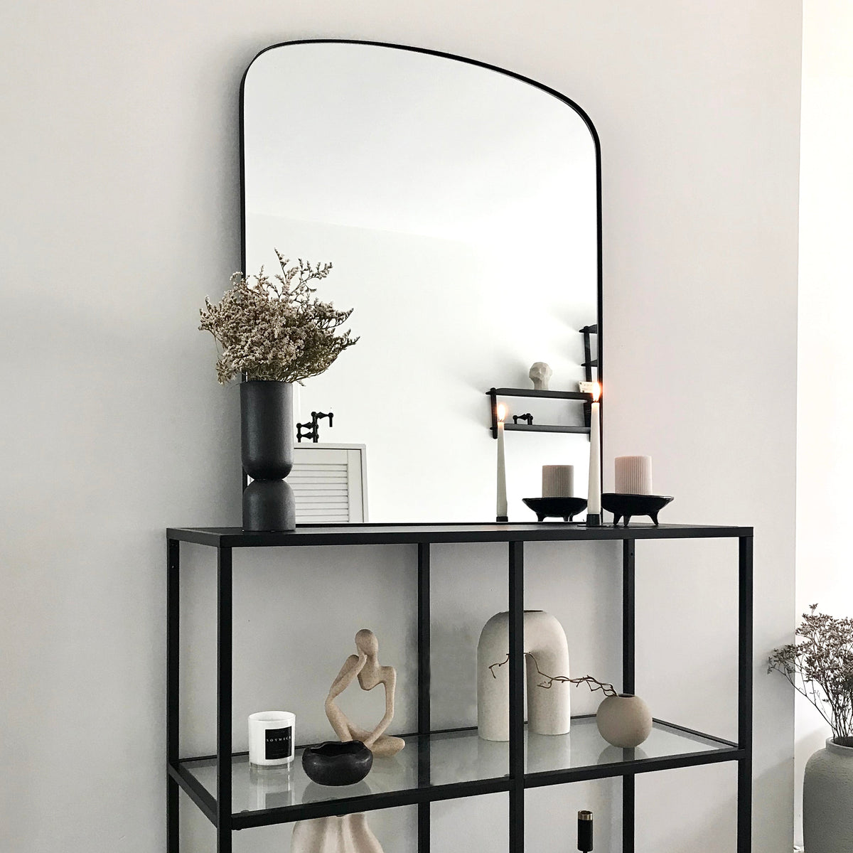 Black contemporary arched metal wall mirror displayed beside window