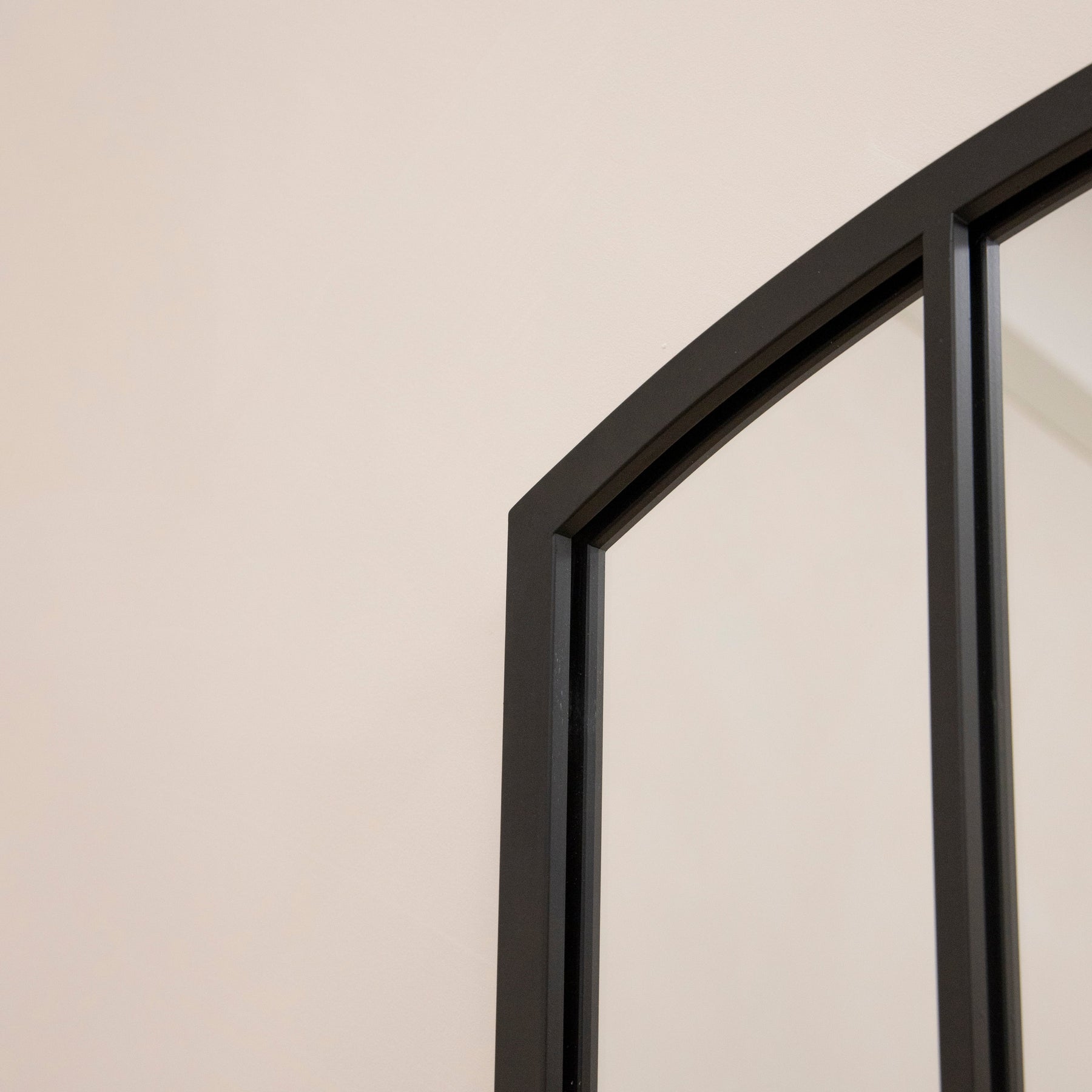 Closeup of Full length black metal window mirror arch