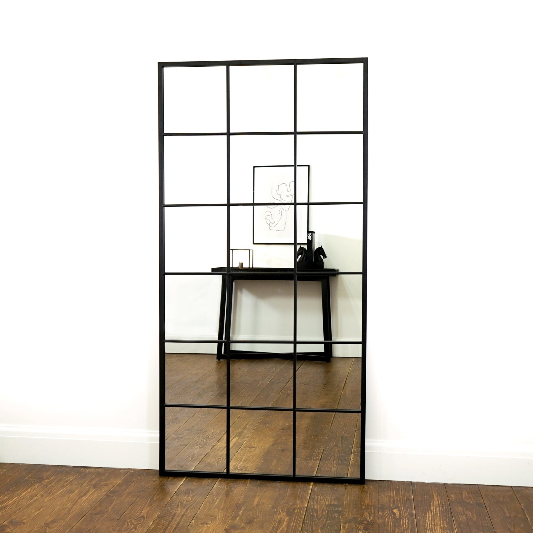 Full length large black metal window mirror leaning against wall