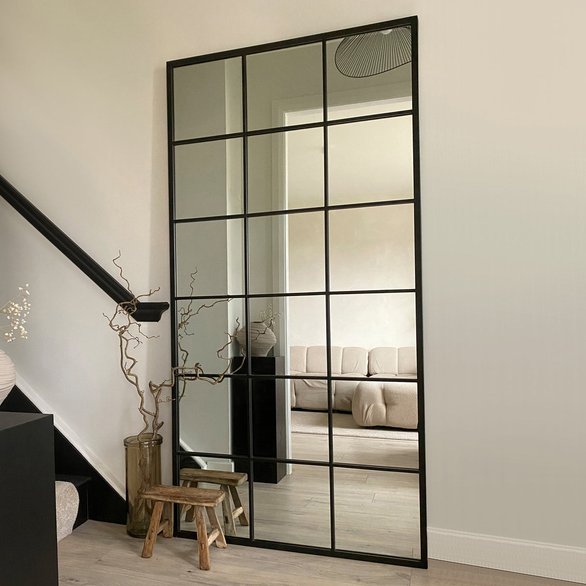 Full length large black metal window mirror leaning against wall