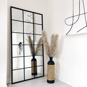 Full length large black metal window mirror beside vase