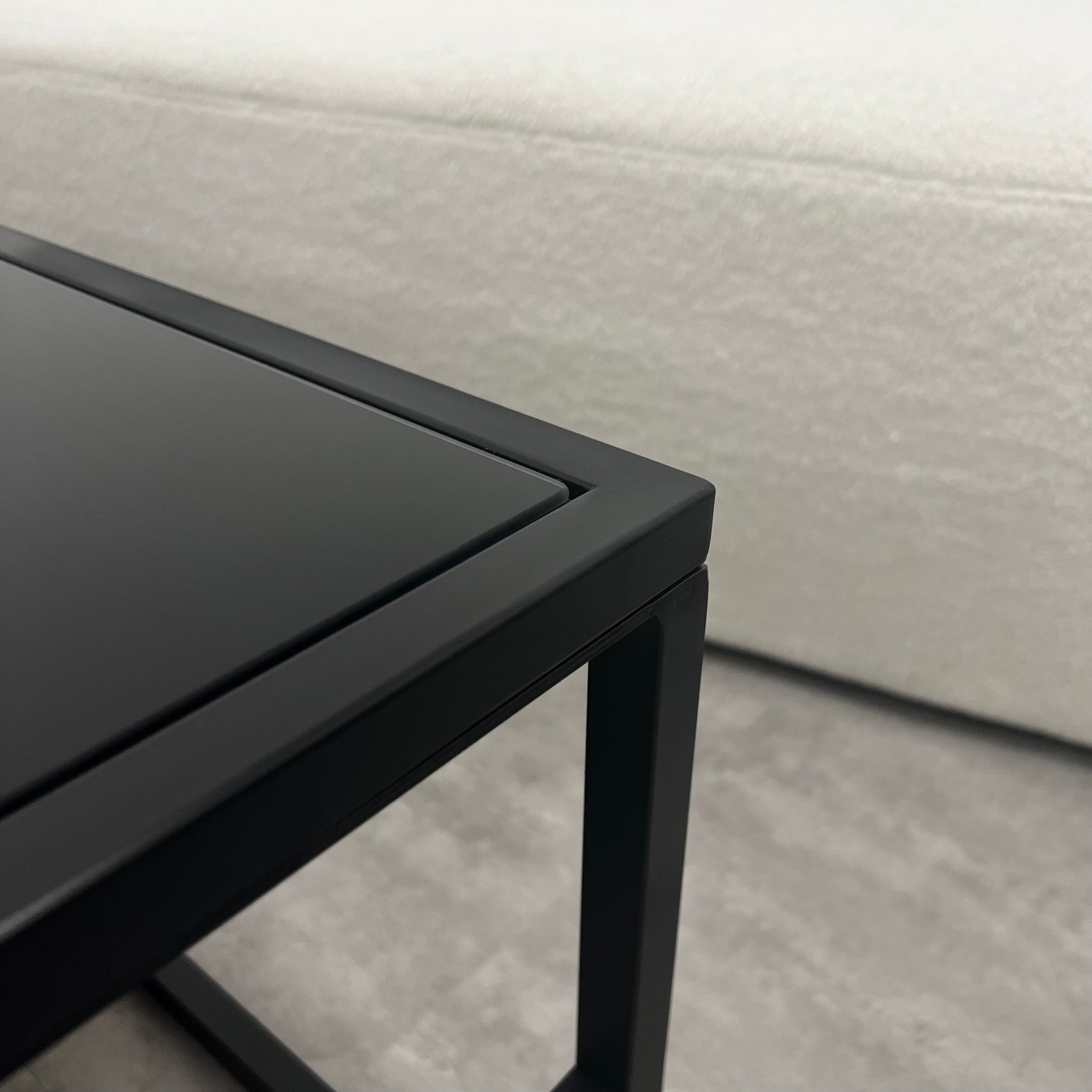 Closeup of Black modern large rectangle tinted mirrored coffee table corner