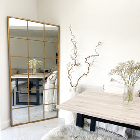 Full length large gold industrial metal window mirror displayed in lounge