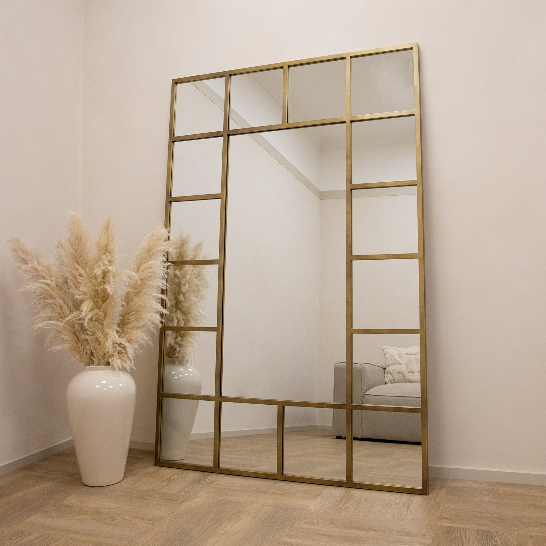 Gold industrial full length metal window mirror leaning against wall