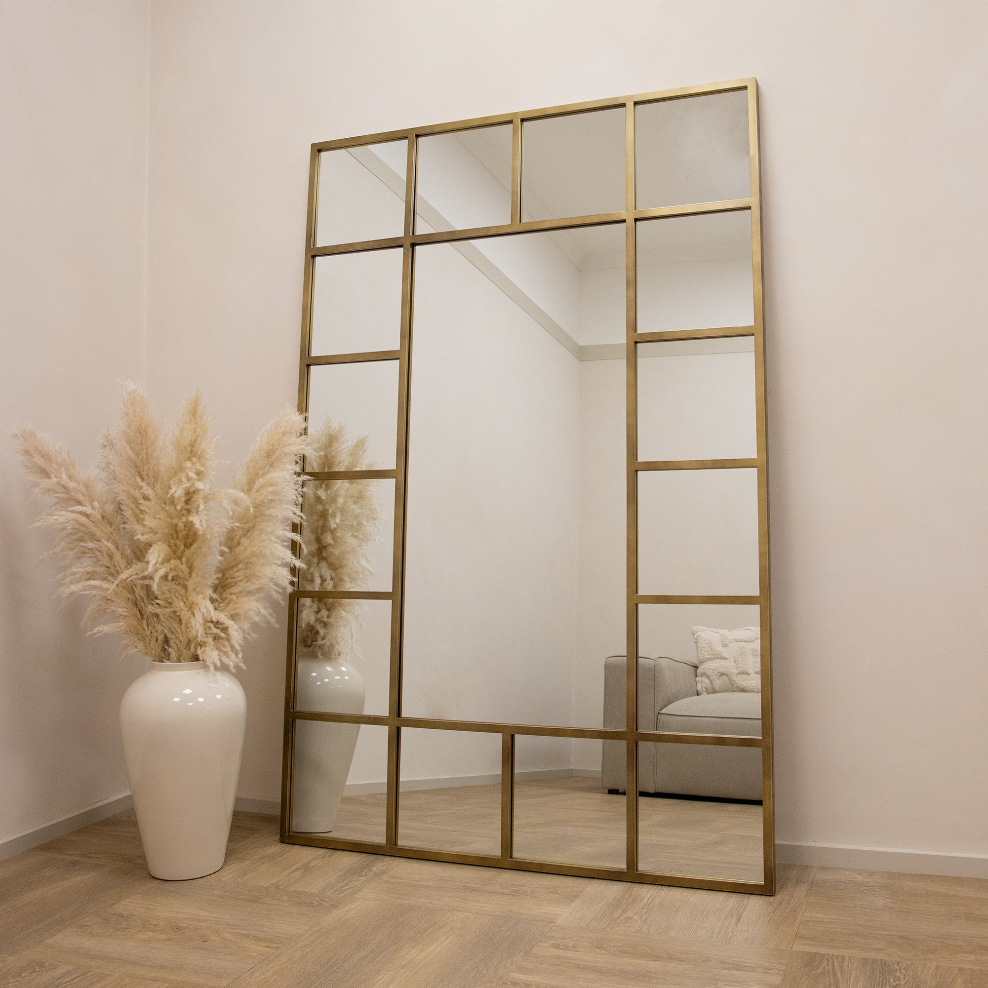 Gold industrial full length metal window mirror leaning against wall