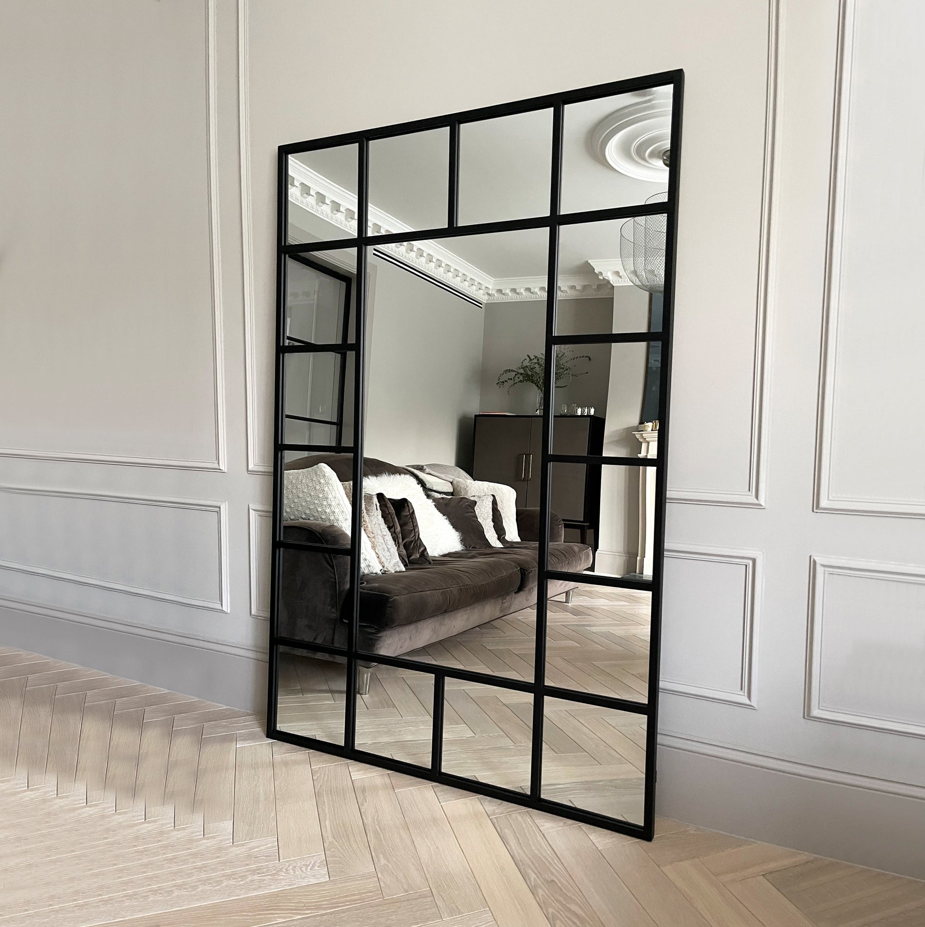 Black industrial full length metal window mirror leaning against wall