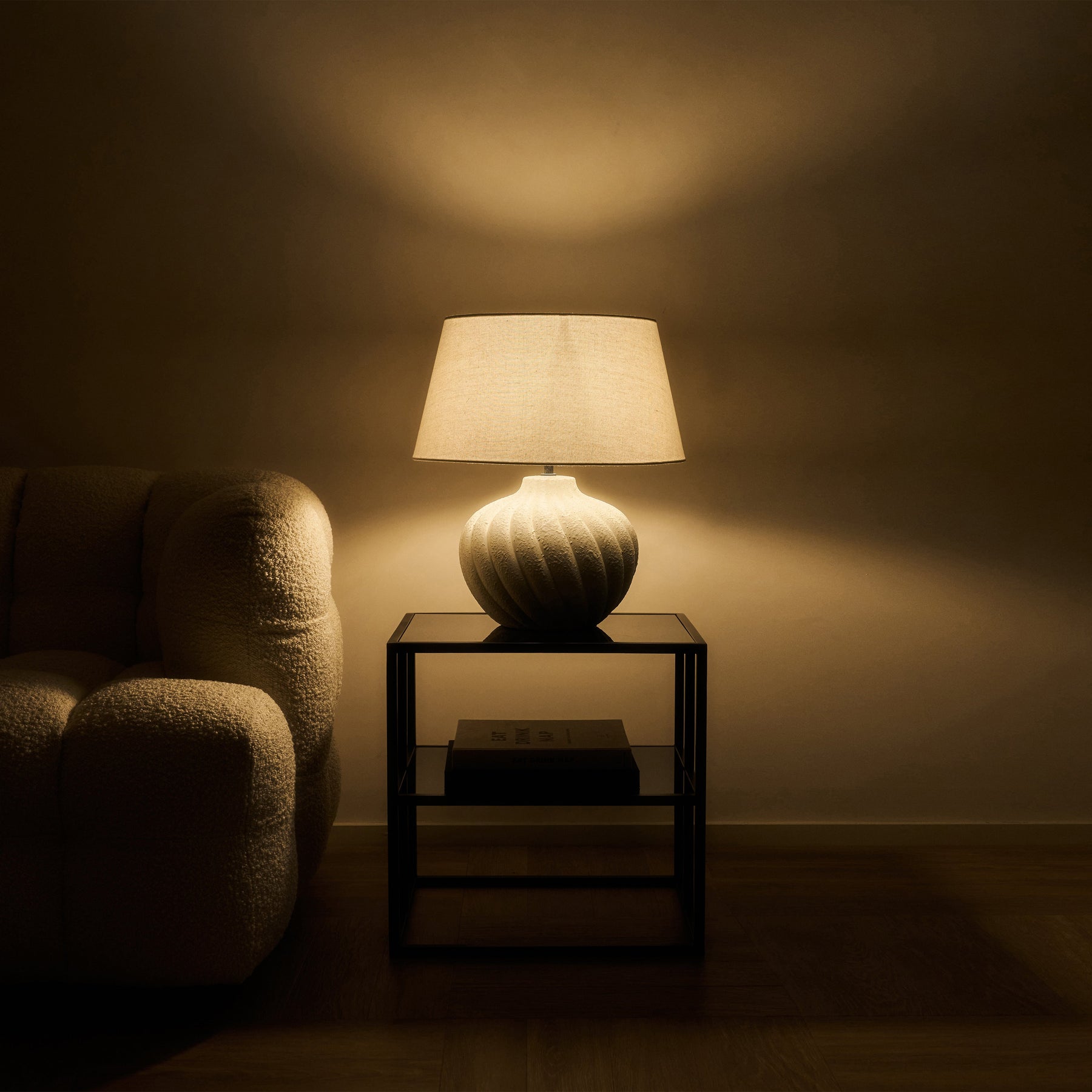 Textured ceramic based table lamp natural shade beside sofa