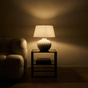 Textured ceramic based table lamp natural shade beside sofa