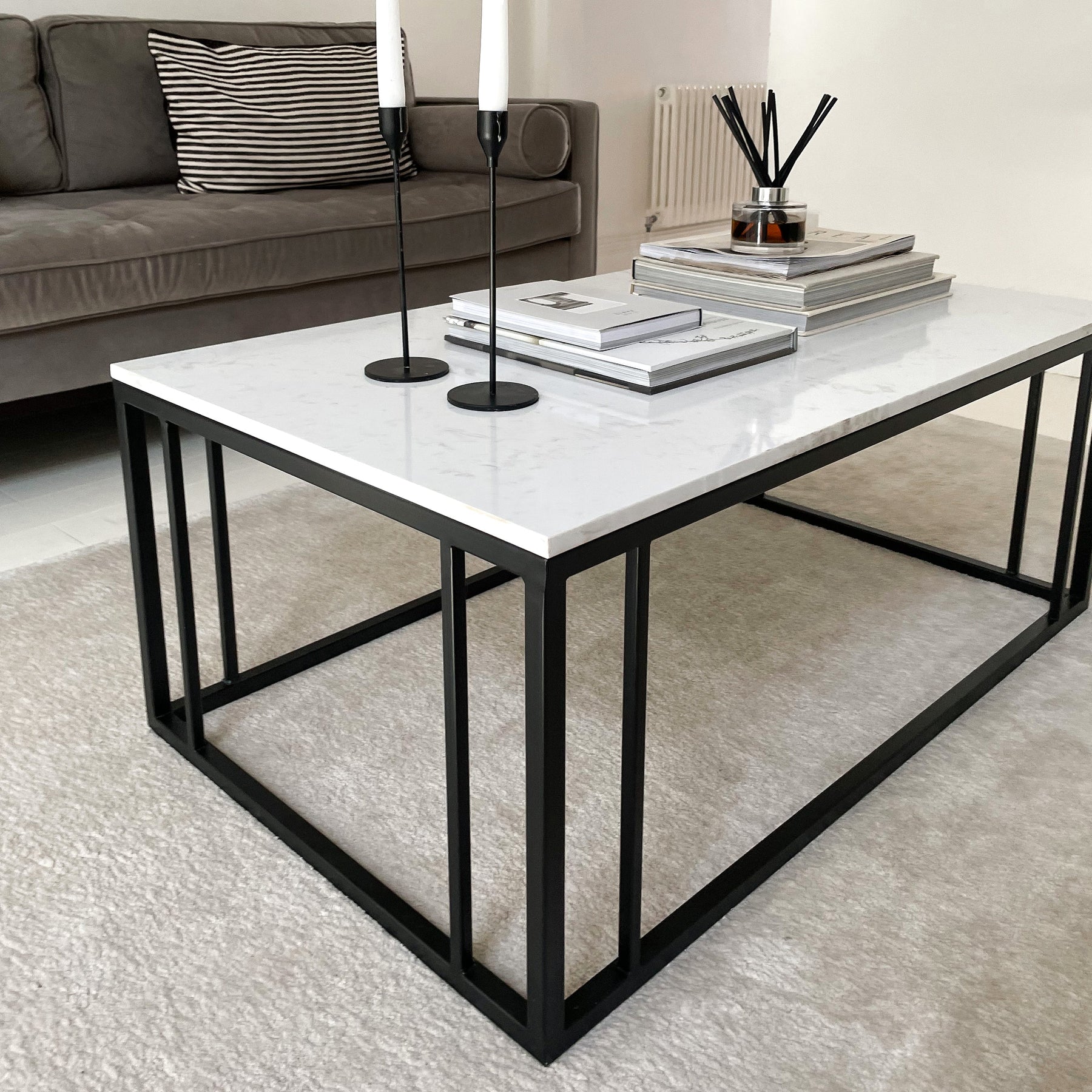 White marble effect rectangular coffee table adorned with candles, books, and incense