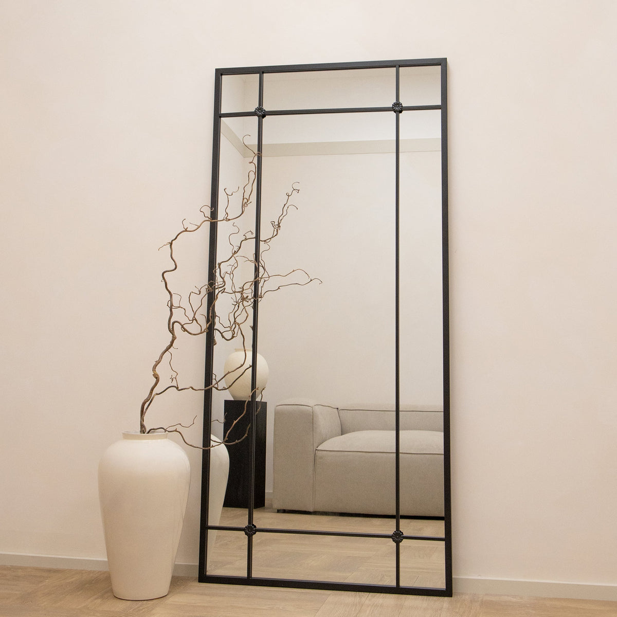 Black industrial full length metal mirror beside vase