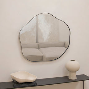 Black metal pond shaped irregular wall mirror displayed above console table