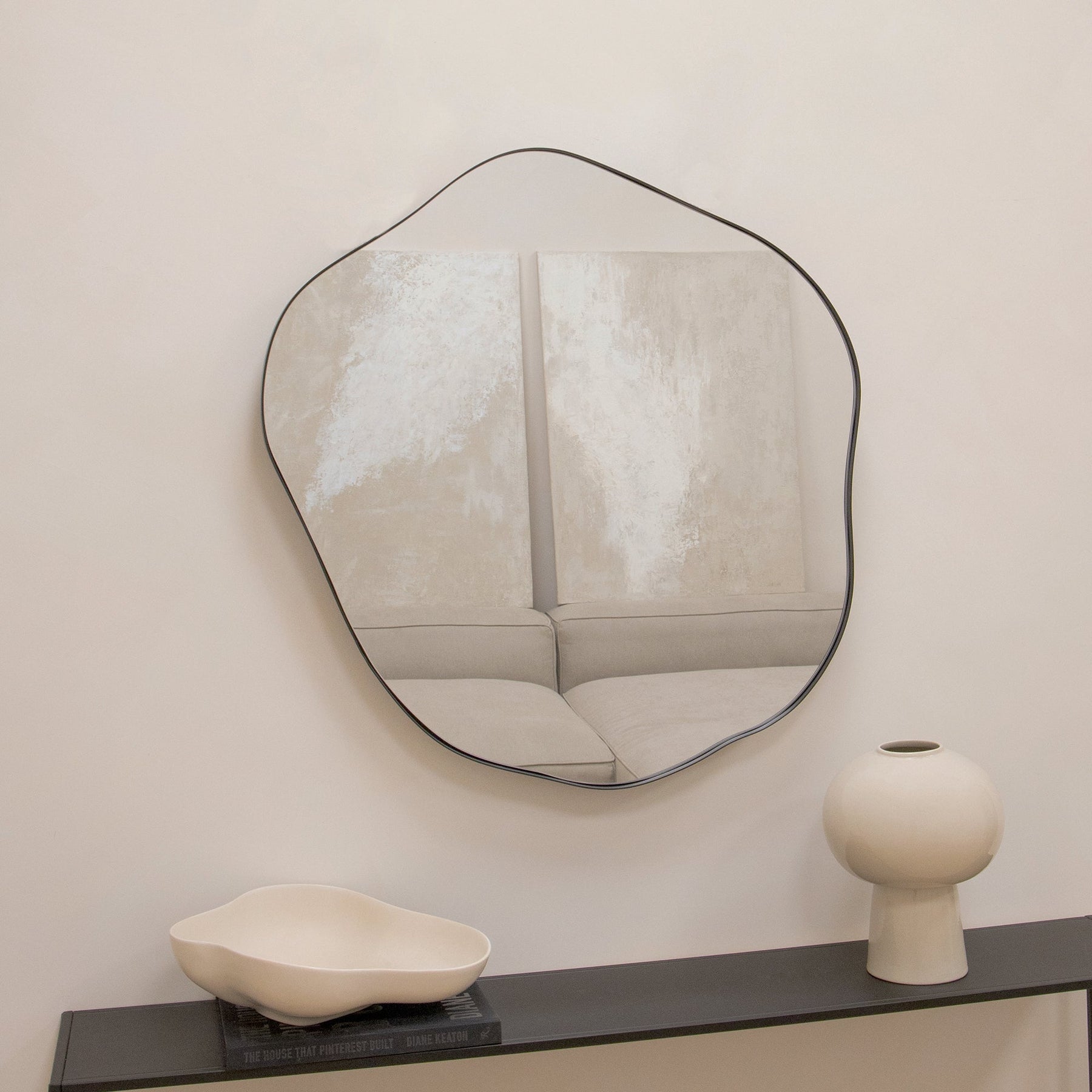 Black metal pond shaped irregular wall mirror displayed on wall