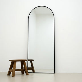 Black Full Length Arched Metal Mirror alternate shot beside wood stool