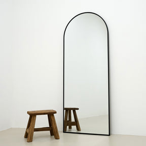 Black Full Length Arched Metal Mirror beside stool