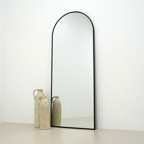 Black Full Length Arched Metal Mirror beside ceramic vases