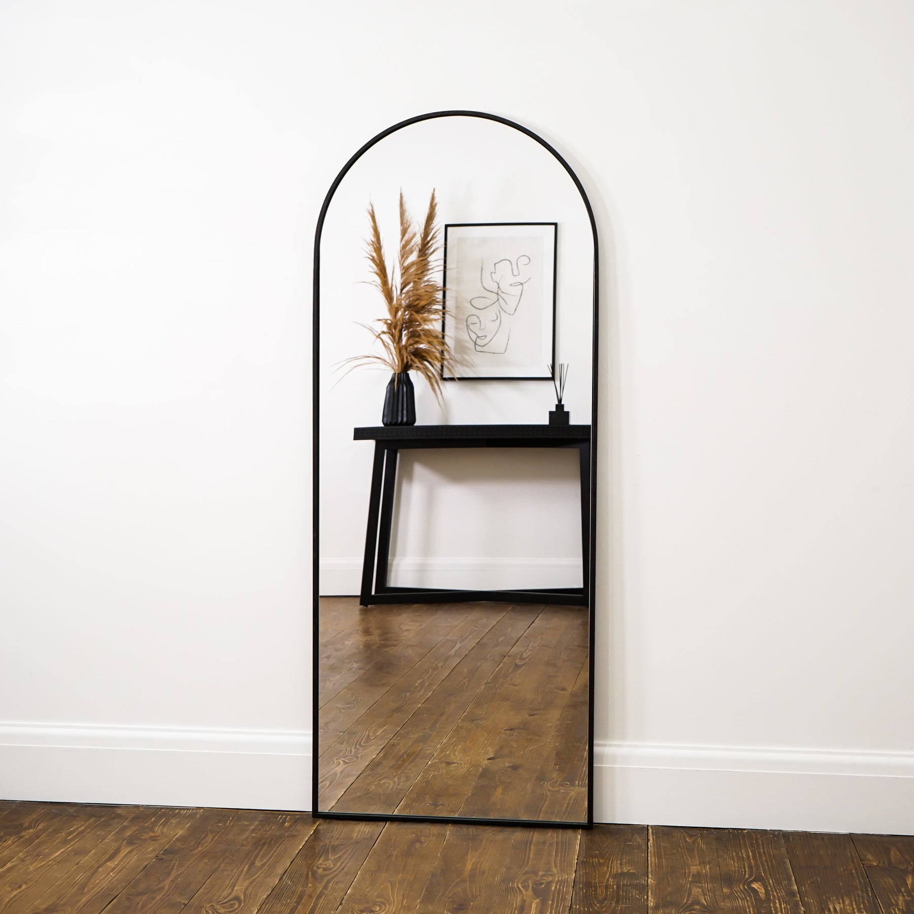 Black Full Length Arched Metal Mirror leaning against wall