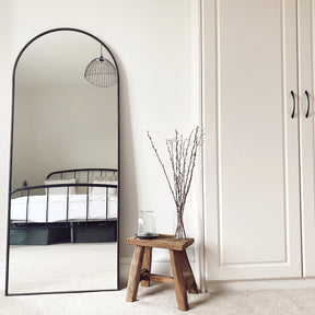 Black Full Length Arched Metal Mirror in bedroom beside bench