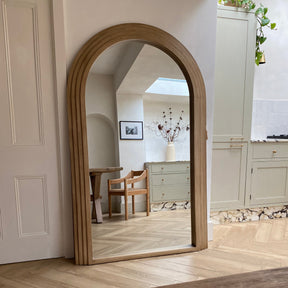 Full Length Arched Washed Wood Mirror leaning against wall in lounge