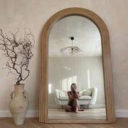 Full Length Arched Washed Wood Mirror beside ceramic vase