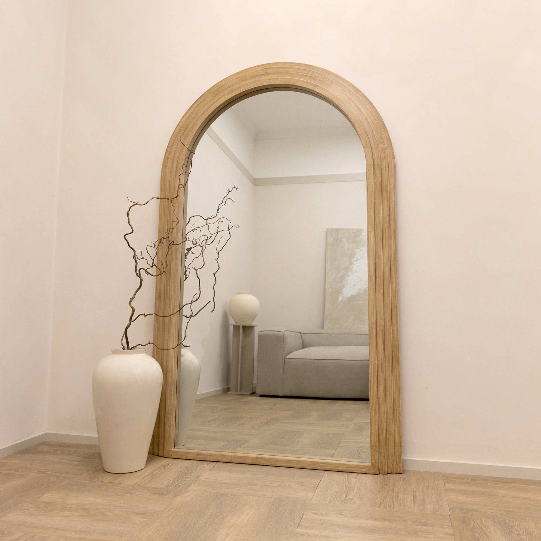 Full Length Arched Washed Wood Mirror beside ceramic vase