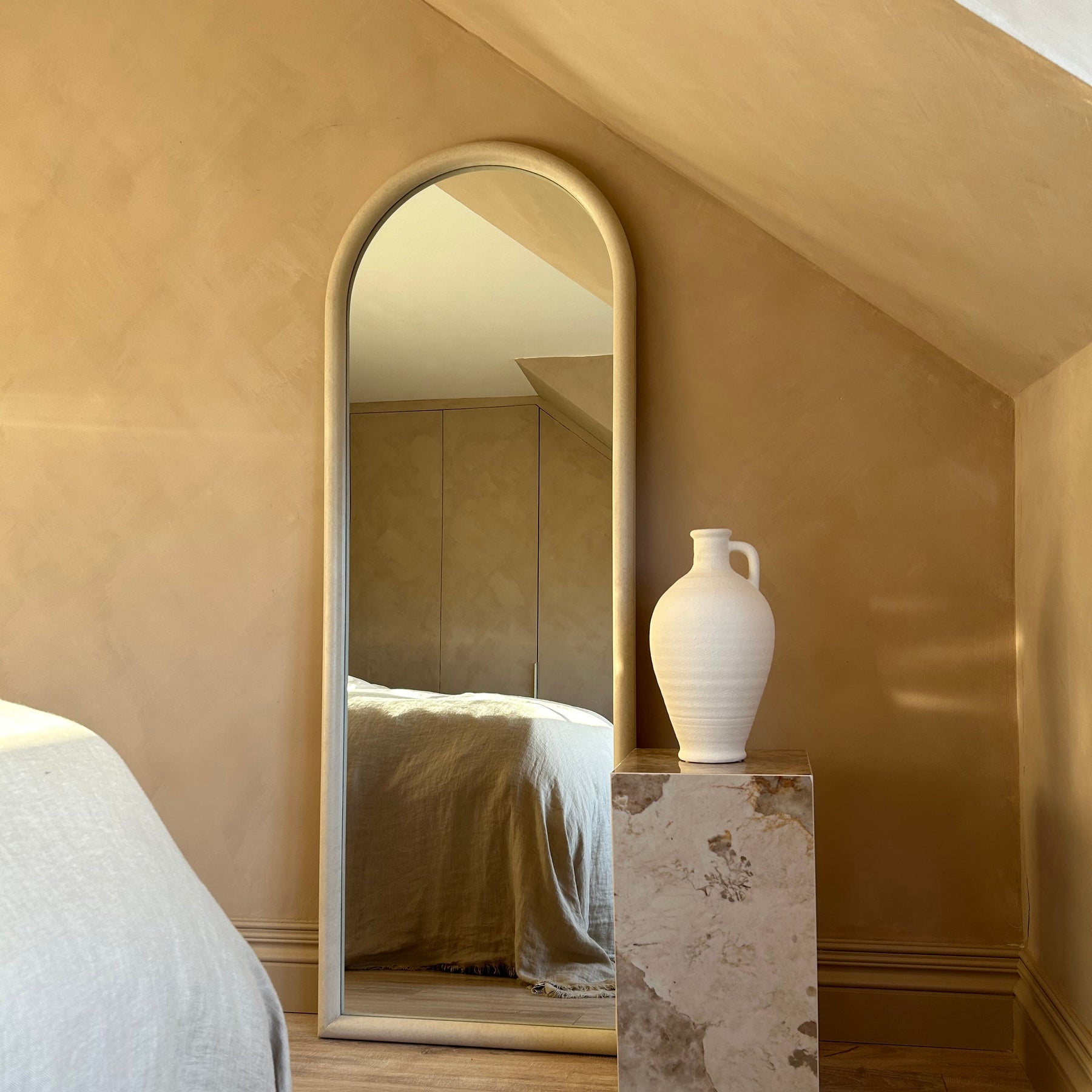 Large arched concrete mirror leaning against wall