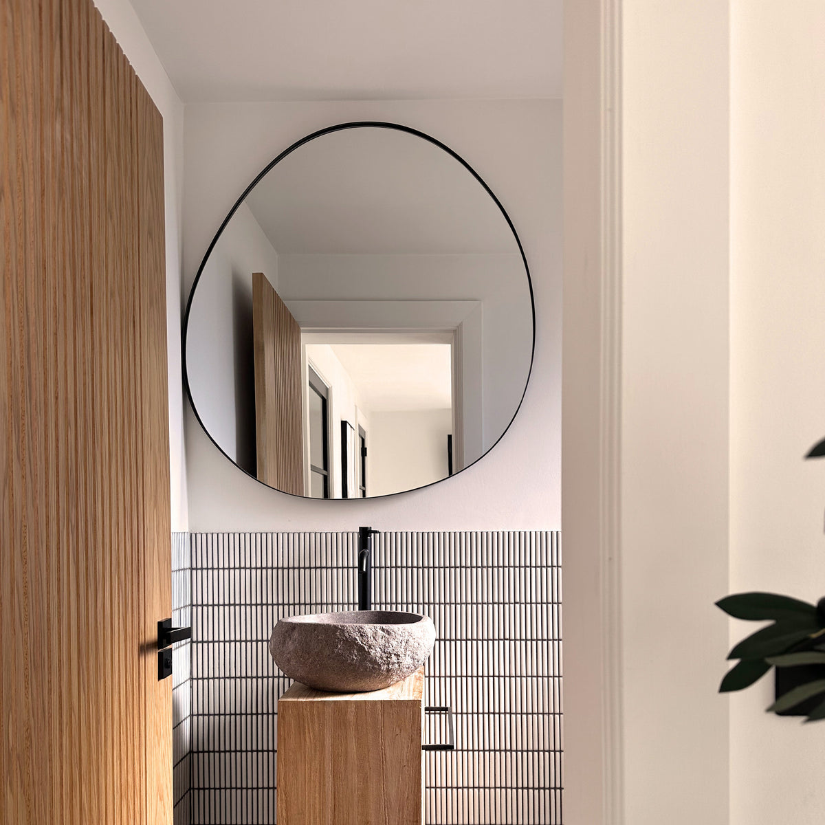 Black metal pond shaped irregular wall mirror displayed in bathroom