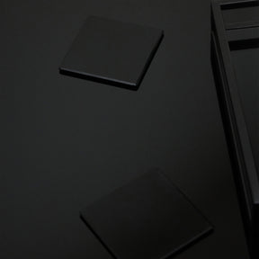 Two black coasters on mirrored glass table