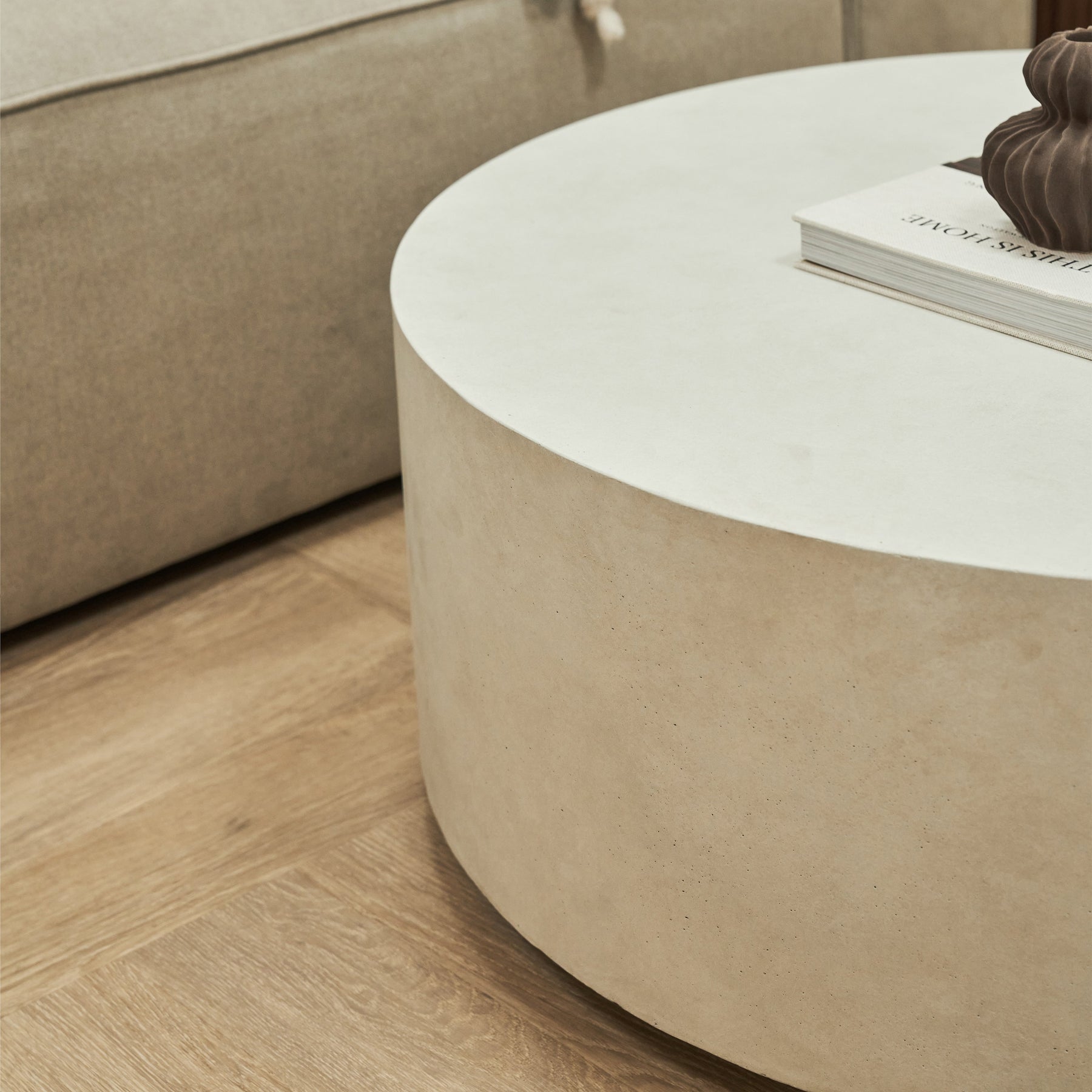 Large minimalist concrete round coffee table displayed beside sofa