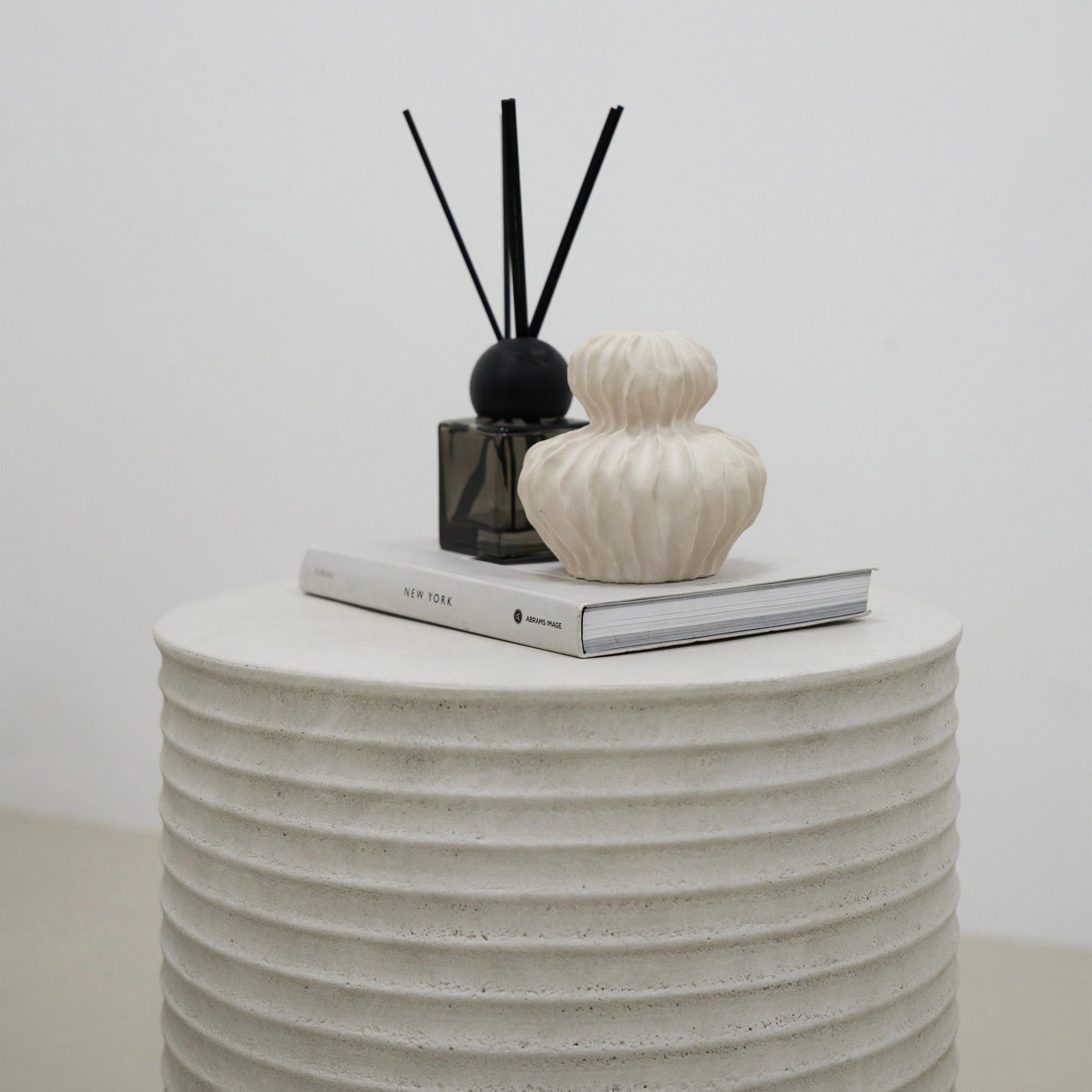 alternate shot of Minimal Concrete Ribbed Side Table adorned with ceramics and book