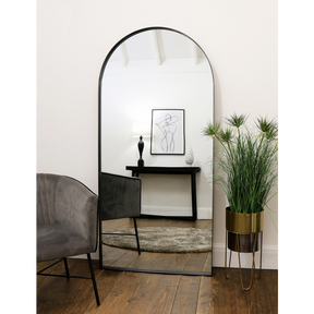 Full length arched black large metal mirror leaning against wall