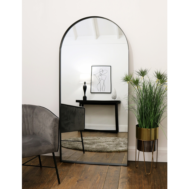 Full length arched black large metal mirror leaning against wall