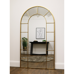 Gold industrial arched full length metal mirror reflecting lounge