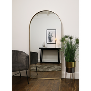 Full length arched gold large metal mirror leaning against wall